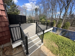 Deck facing the home with sliding glass doors and surrounding rail system
