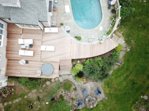 arial-view-pool-deck - Decks by RTC Overhead view of curved IPE hardwood deck wrapping around a pool and connecting to patio spaces in Farmington, CT
